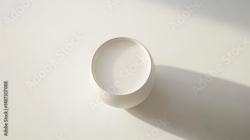 Wallpaper Mural Minimalist composition of white milk in spherical bowl casting shadow on surface Torontodigital.ca