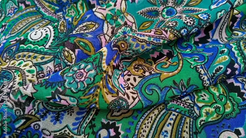 Paisley patterned fabric detail wrinkled moving background, featuring curved, teardrop shaped motifs of Persian origin with vibrant colors like blue and green, texture Paisley patterned fabric detail wrinkled moving background, featuring curved, teardrop shaped motifs of Persian origin with vibrant colors like blue and green, texture
