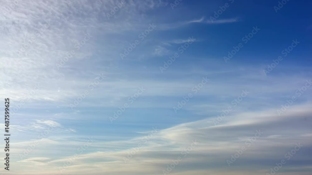 Expansive clear blue sky filled with soft white cirrus clouds creating a serene and ethereal atmosphere for background use. Expansive clear blue sky filled with soft white cirrus clouds creating a serene and ethereal atmosphere for background use.