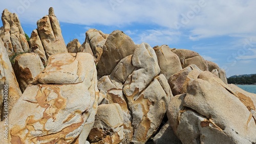 Rock formations rise along the clear shoreline of La Gi town, Vietnam, under a bright blue sky.