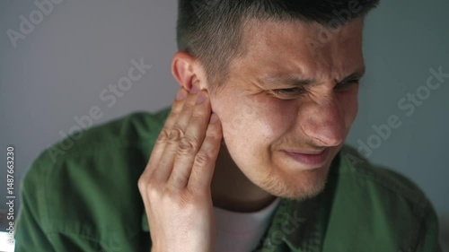 Wallpaper Mural a young man in a green shirt has ear pain Torontodigital.ca