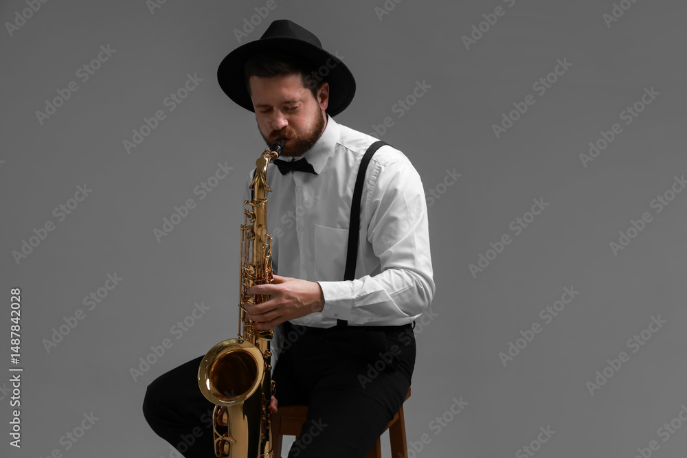 Naklejka premium Professional musician playing saxophone on grey background