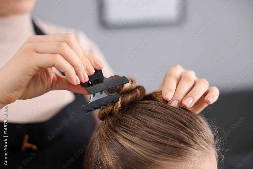 Fototapeta premium Hairdresser doing girl's hairstyle in salon, closeup