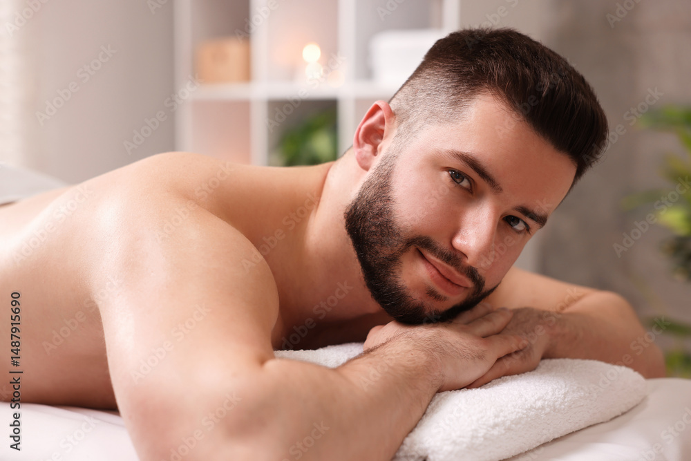 Naklejka premium Handsome man lying on massage table in spa salon