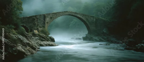 Panel kuchenny z motywem A tranquil stone bridge arches gracefully over a mist-covered river, surrounded by lush greenery and enshrouded in soft morning mist.
