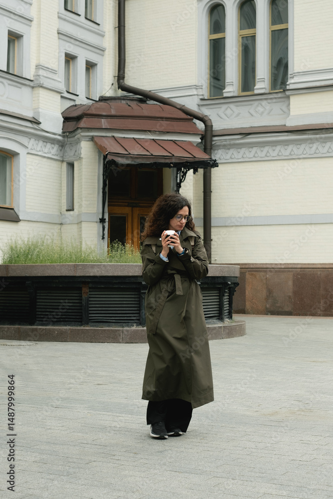 Fototapeta premium Stylish woman walking city streets with coffee