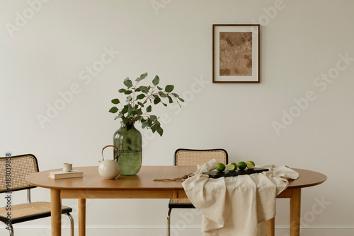 Bright interior with minimalist setup, a dining table styled with greenery, teapot, and limes on neutral linen. Scandinavian and Japanese design influences.