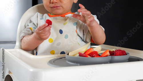 Fotografía Baby taking fruit pieces from a grey silicone plate, baby led weaning