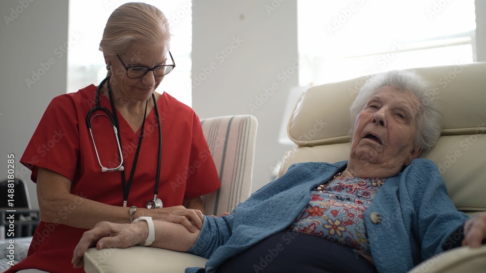 Obraz premium A caregiver gently massages the arm of an elderly woman, offering relaxation and comfort in a bright clinical setting during afternoon hours.