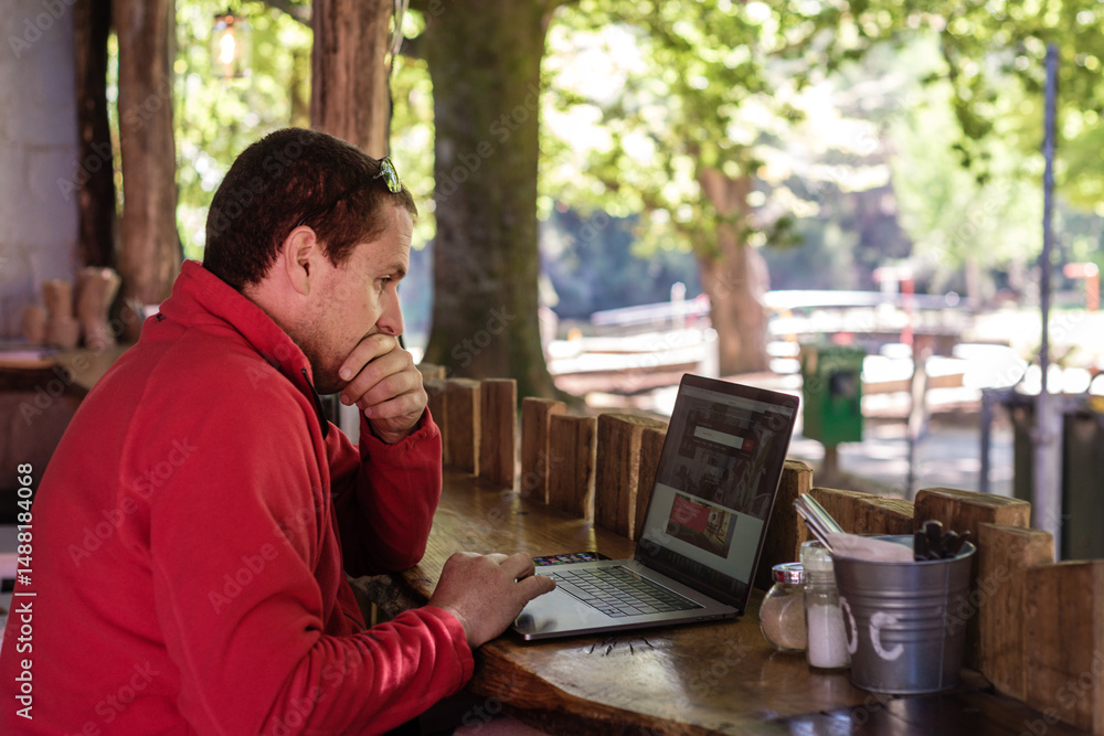 man using laptop in cafe whilst on holidays man using laptop in cafe whilst on holidays