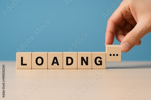 A human hand places the final cube completing the word loading with ellipsis