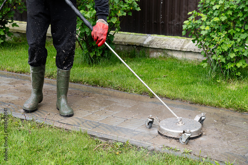 Professional paving stone cleaning. Cleaning a stamped concrete patio with a pressure washer in a residential garden during the day