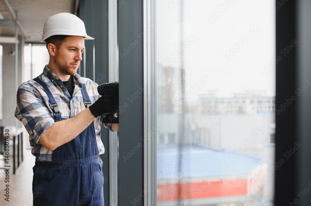 Construction worker installing window in modern office building Construction worker installing window in modern office building