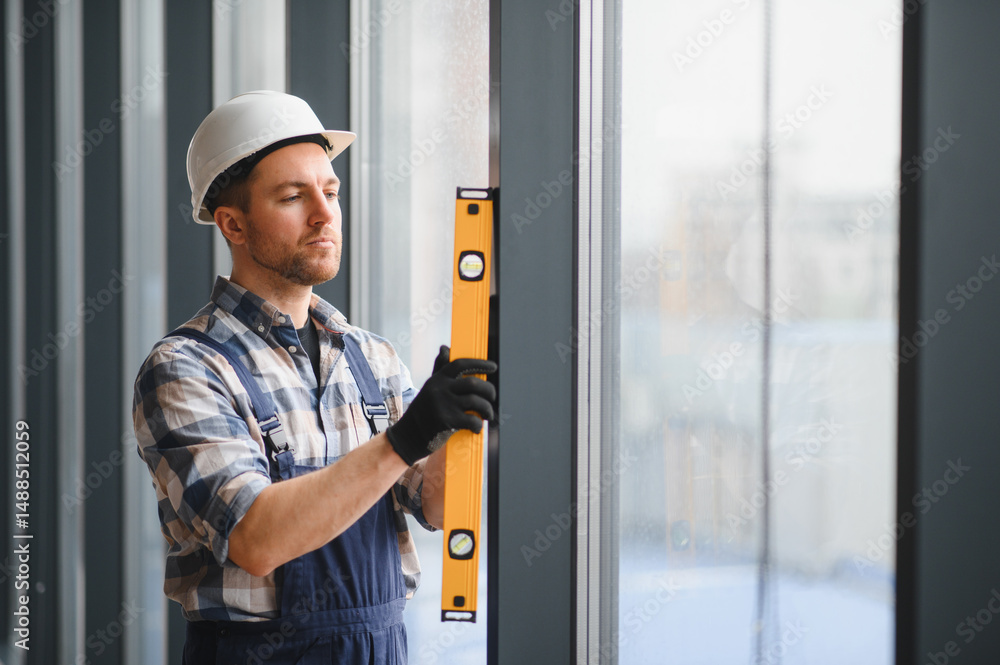 Construction worker checking window frame with spirit level ensuring proper alignment Construction worker checking window frame with spirit level ensuring proper alignment
