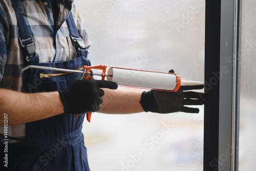 Construction worker applying sealant to window frame