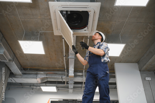Hvac technician repairing air conditioning unit in office building