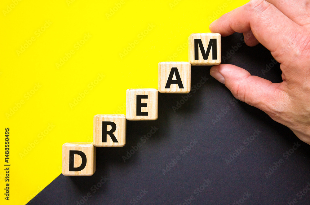 Obraz premium Dream symbol. Concept word Dream on beautiful wooden blocks. Beautiful yellow and black background. Businessman hand. Business lifestyle dream concept. Copy space.