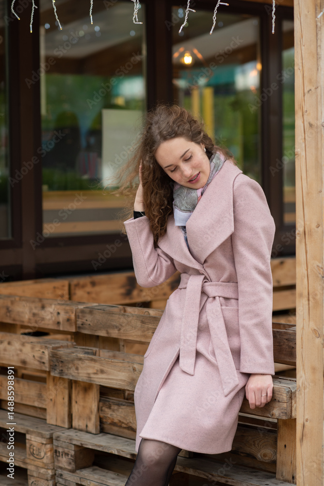 Fototapeta premium Portrait of a beautiful red-haired girl in a gray coat in a city park.