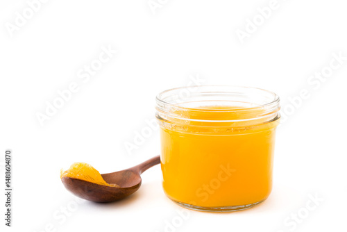 Ghee or clarified butter in jar and wooden spoon on white background