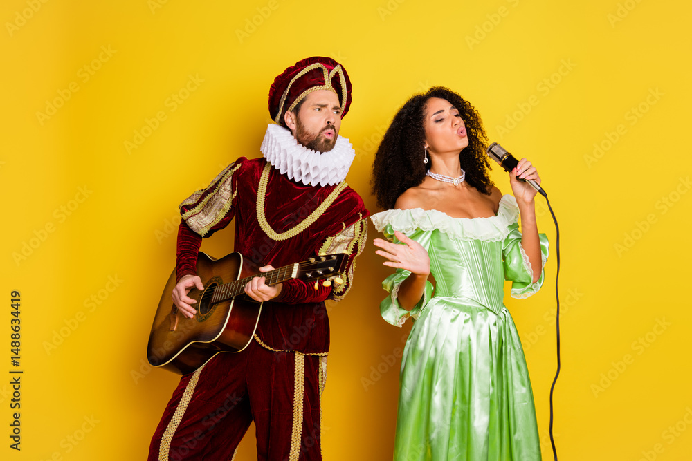 Couple in vibrant renaissance costumes singing and playing guitar against a striking yellow background Couple in vibrant renaissance costumes singing and playing guitar against a striking yellow background