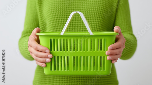 Person holding green plastic shopping basket