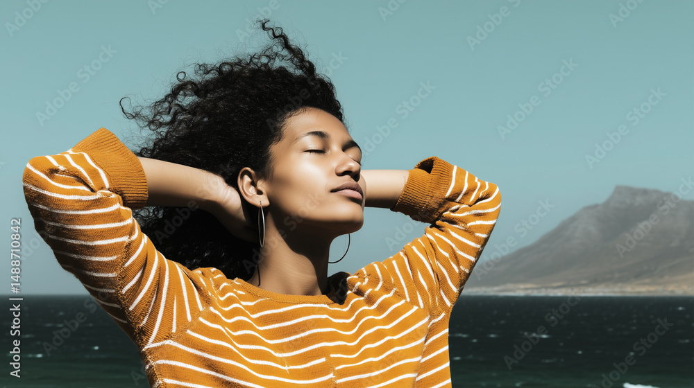 Relaxed young woman enjoying the sea breeze with mountains in the background