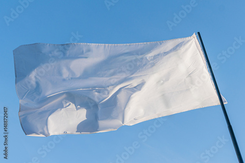 Large white flag with subtle texture, attached to two poles, slightly off-center against an out-of-focus overcast sky Candid photograph style, daylight lighting conditions
