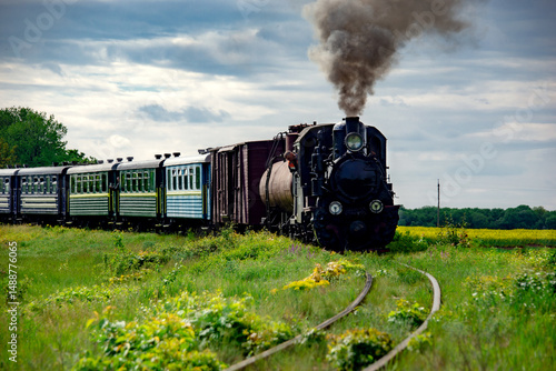 Steam locomotive on the move. Narrow gauge railway.The locomotive smokes, giving a signal. Weekend tour. Tourism Ukraine. Picturesque route.