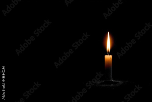 Single candle flame burning brightly in complete darkness.