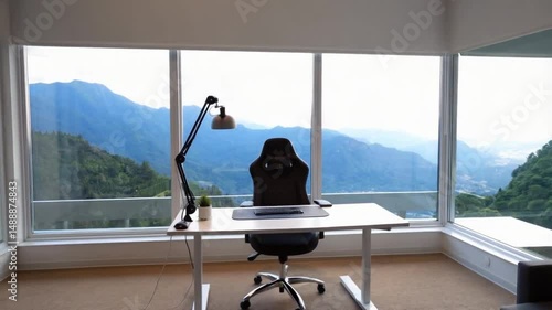 A desk and chair face a large window with a mountain view in a bright and modern office space