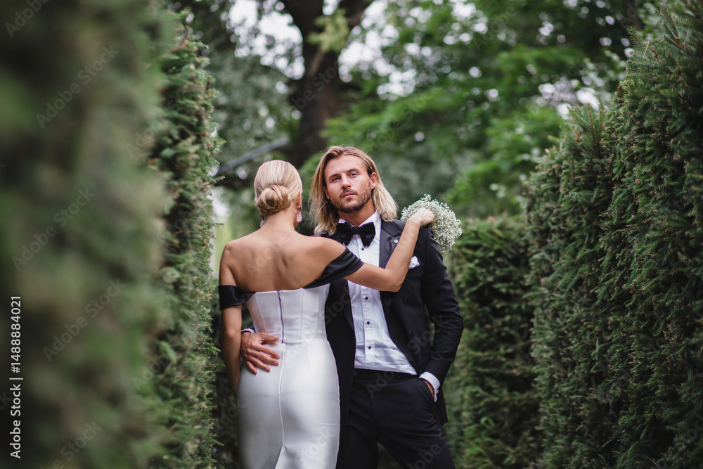 Stylish young newlywed couple posing in green park Stylish young newlywed couple posing in green park