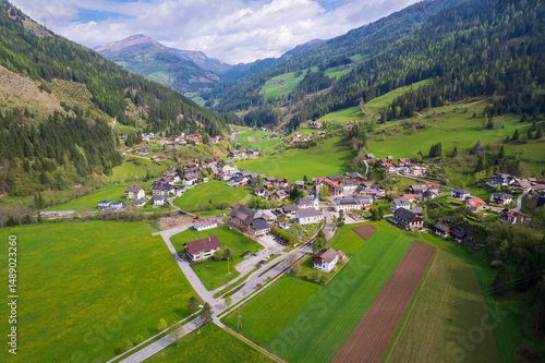 Aerial view of Ebene Reichenau, a picturesque Austrian village nestled in a lush green valley in Carinthia region, surrounded by mountains and farmland under a bright sky