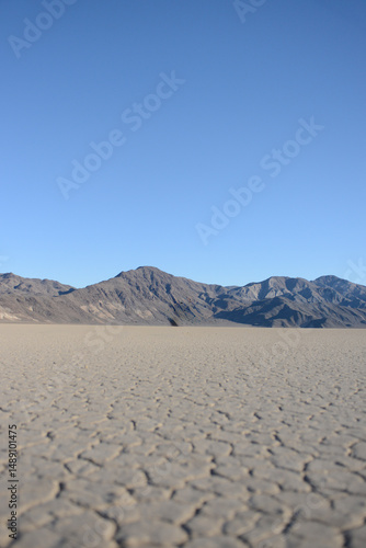 Racetrack Playa cracked dried lake bed with mountains and blue sky in Death Valley