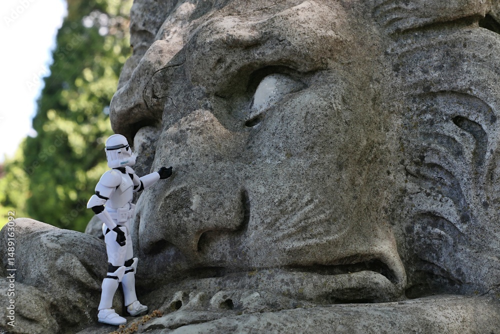 Naklejka premium Star Wars articulated action figure of Clone Trooper touching large stone statue of sleeping lion. 