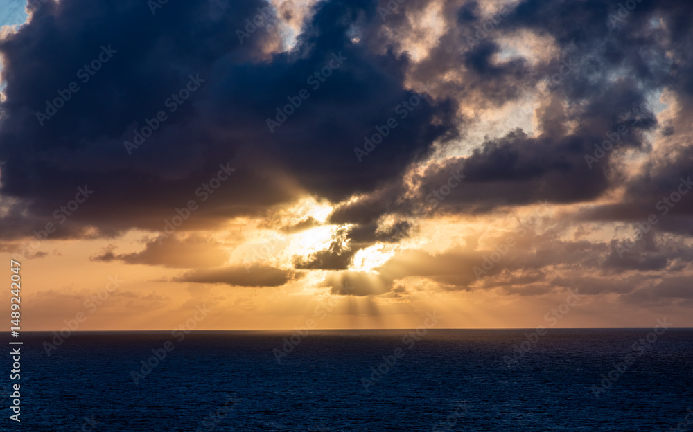 Naklejka premium Dramatic Cloudscape Over the Pacific Ocean During Sunset with Sunbeams