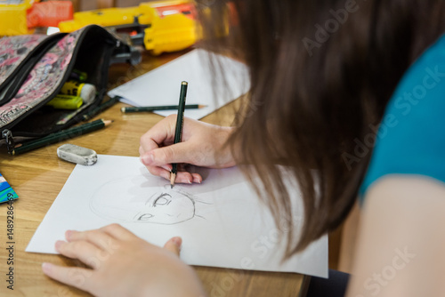 Young teenage girl creating artwork, drawing Manga and stencilling at the table