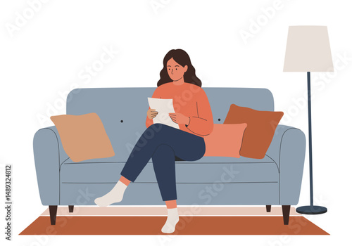 Woman reading a letter while sitting on a sofa in a cozy living room  