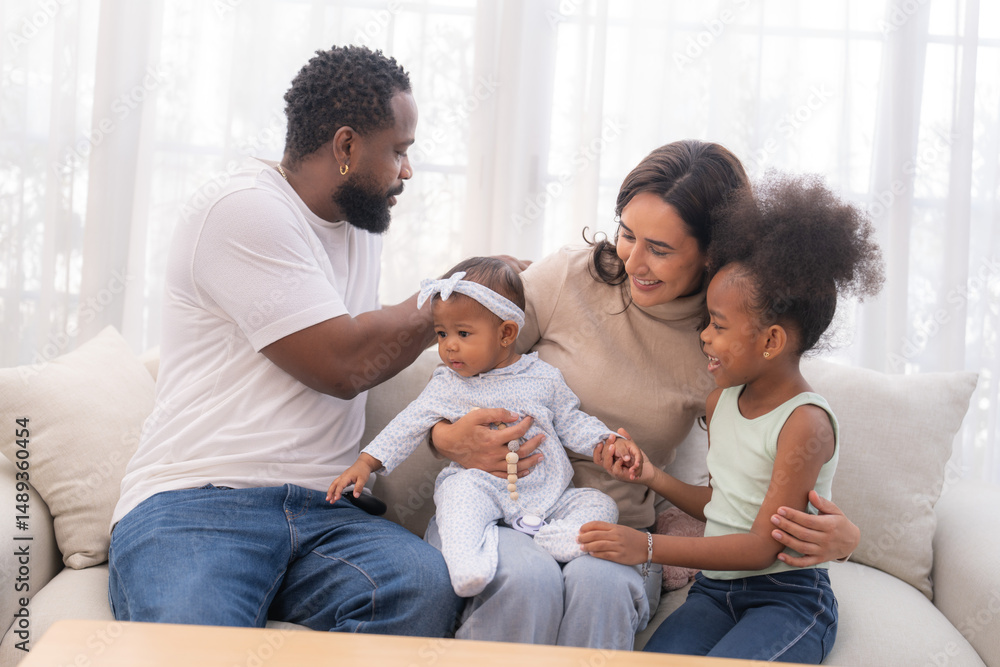 Happy family sitting together on a sofa, spending quality time and smiling while enjoying snacks at home in a warm and cozy living room. Happy family sitting together on a sofa, spending quality time and smiling while enjoying snacks at home in a warm and cozy living room.