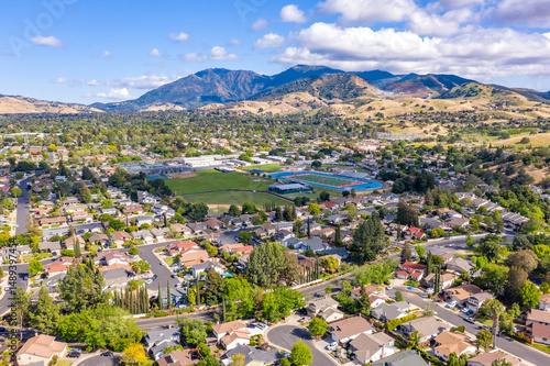 Aerial drone view of Concord, California, featuring residential neighborhoods, a sports complex, and Mount Diablo in the scenic background under a partly cloudy blue sky.