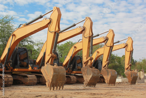 Lots of excavators parked on construction area of industrial building in construction site under the blue sky background.Earthmoving construction equipment