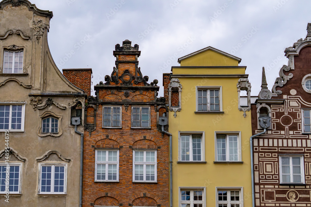 Fototapeta premium fragment of historic townhouse facades in Gdańsk, showcasing a variety of architectural styles and vibrant facade colors. The buildings include richly decorated, brick, and plastered structures, creat