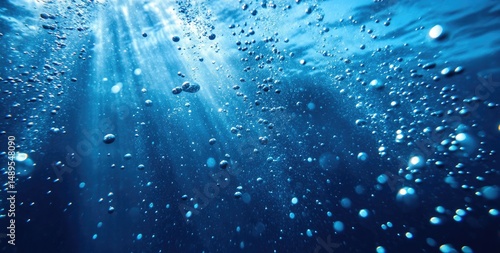 Sunlight streams through the surface of the ocean, illuminating bubbles rising to the surface