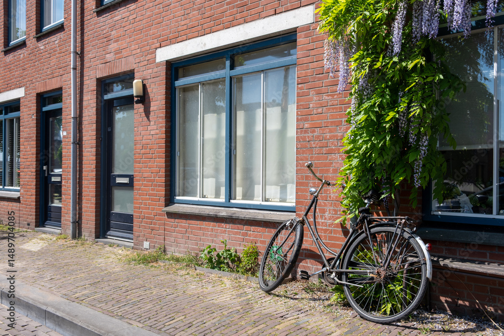 Bicycle parked on sidewalk in front of brickwall building in Delfshaven. Biking in Holland
