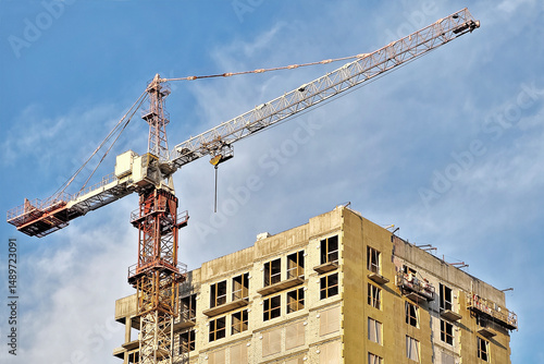 Construction crane. Building site, construction of a residential building. Brick multi-building residential house.