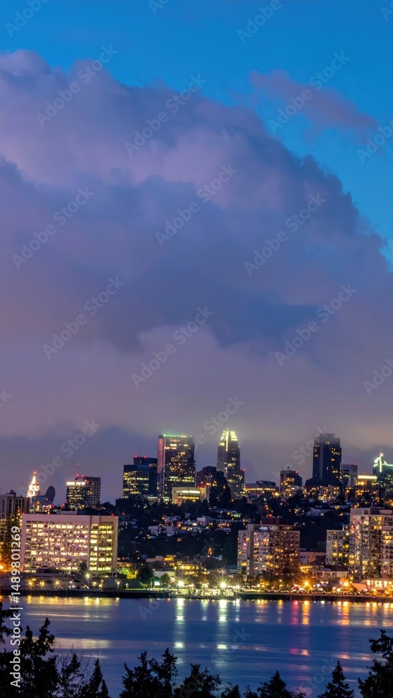 Fototapeta premium Vibrant City Skyline at Dusk with Lights and Low Cloud Reflections