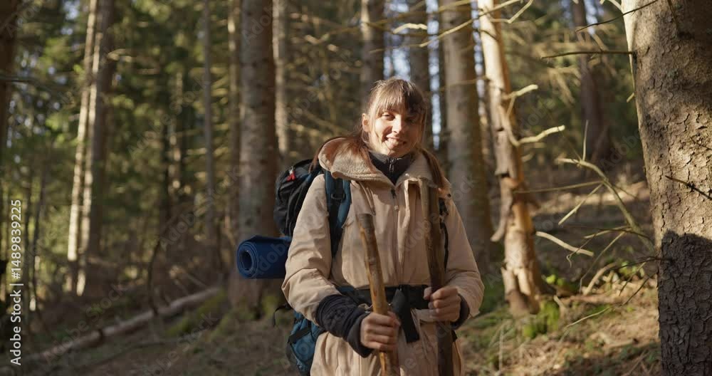 Girl in hiking clothes with backpack posing and looking at camera during her hike in wild forest. Portrait of a girl hiking in a sunny forest Girl in hiking clothes with backpack posing and looking at camera during her hike in wild forest. Portrait of a girl hiking in a sunny forest