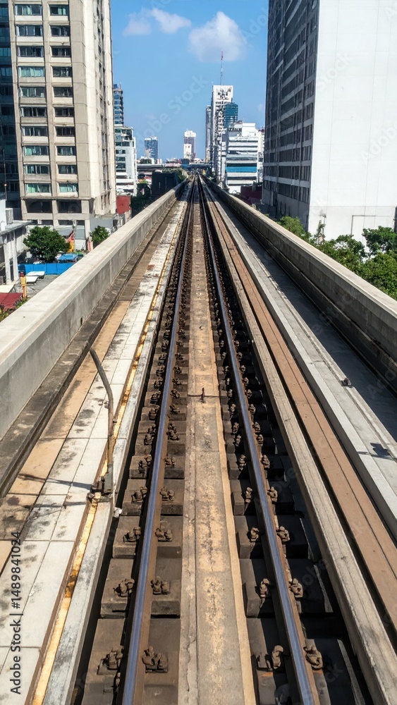 Naklejka premium Urban Rooftop View of Train Track under Bright Blue Sky