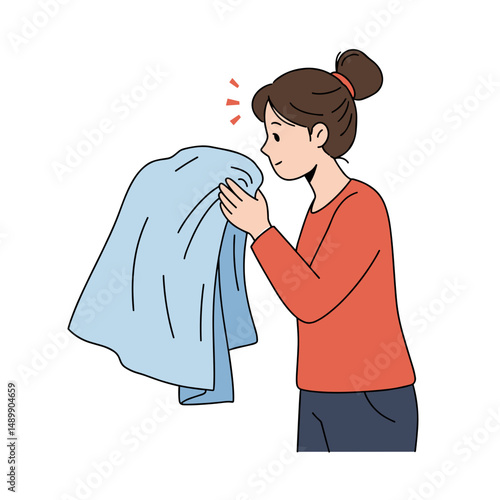 Woman smelling fresh laundry while enjoying the comforting scent of fabric at home