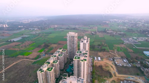 Aerial drone shot orbiting opulent high end multi story residential complex society with multiple towers and huge blue swimming pool in the middle showing the lavish living in Gurgaon Delhi