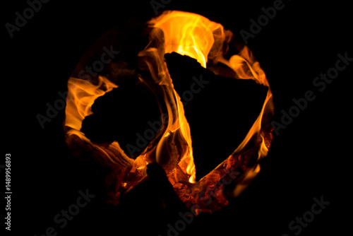 Fiery peace symbol burning in darkness – artistic flame light silhouette at night